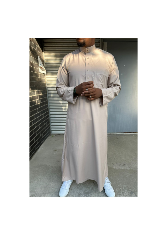 Homme portant un qamis saoudien couleur sable à manches longues, avec col officier et boutons, offrant un style élégant et raffiné.