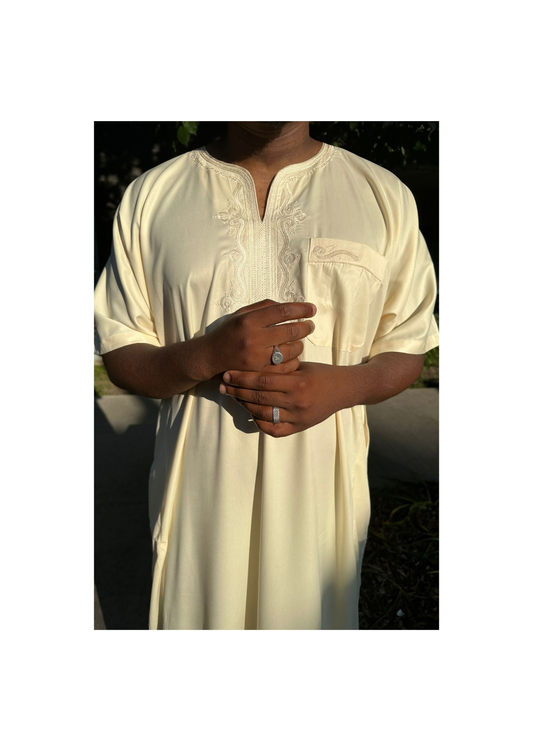 Homme portant une djellaba beige avec broderies traditionnelles sur le col et la poche poitrine
