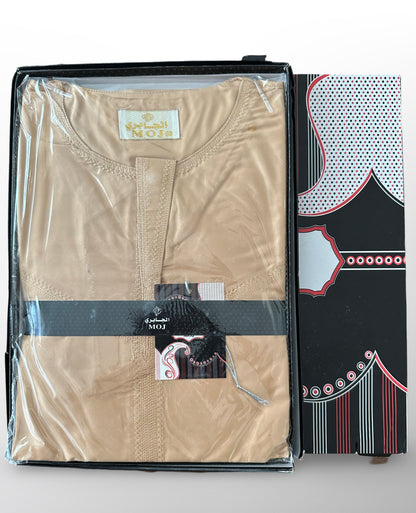 Qamis beige plié dans un emballage transparent avec boîte noire et motifs rouges et blancs, marque MOJ.